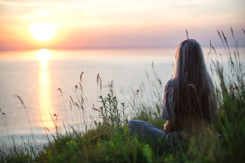 Photo of Woman Sitting on Grass During Golden Hour